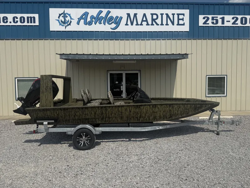 The Image of A 2027 Lowe Outlet 20-CATFISH boat on a trailer in front of a marine shop. - 1