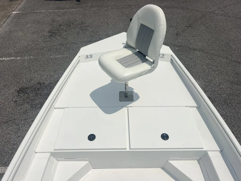 Slide: The Image of A white boat with a single swivel seat on the front deck, surrounded by gray asphalt. - 5