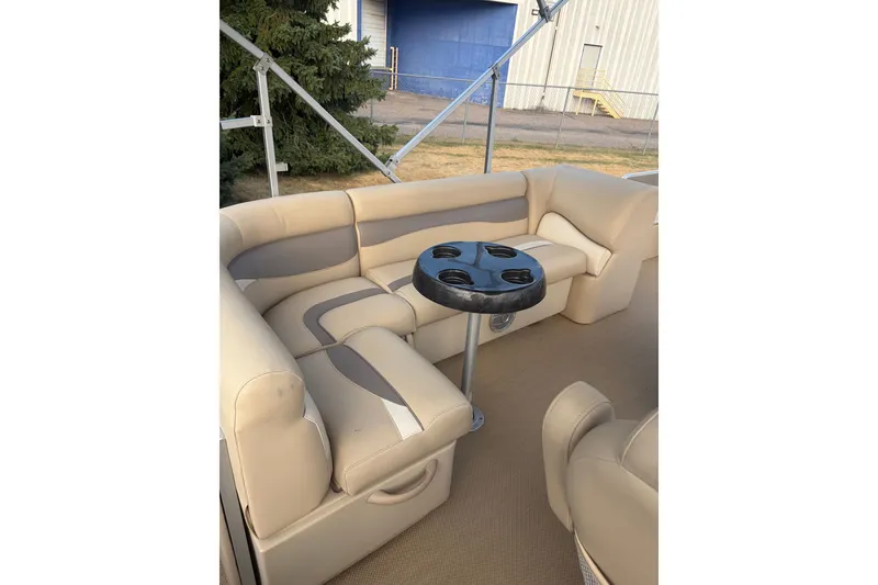 Slide: The Image of 2015 Sweetwater 2286 boat interior with beige seating and cupholder table. - 8