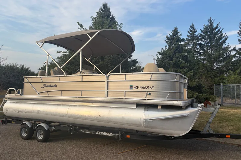 Slide: The Image of 2015 Sweetwater 2286 pontoon boat on trailer, parked outdoors with trees in background. - 4