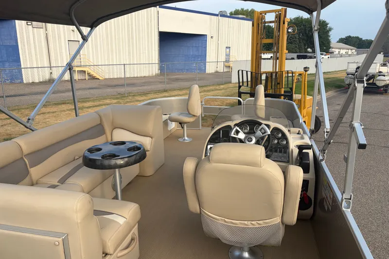 Slide: The Image of 2015 Sweetwater 2286 pontoon boat interior with beige seating and steering console. - 9