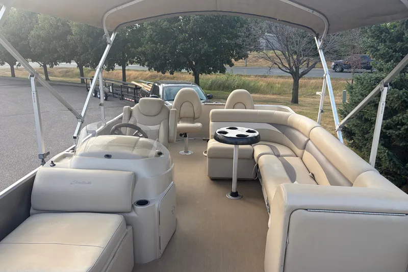 Slide: The Image of 2015 Sweetwater 2286 pontoon boat with beige seating and canopy, parked outdoors. - 7