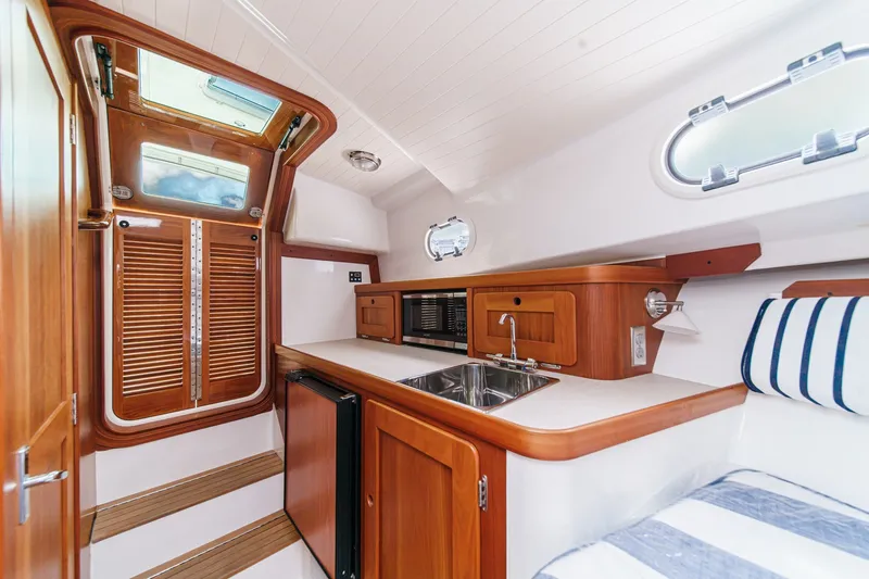 Slide: The Image of Interior of 2020 Hunt Yachts Surfhunter 32, featuring a compact kitchen and wooden cabinetry. - 48