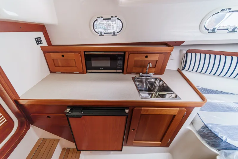 Slide: The Image of Compact galley in 2020 Hunt Yachts Surfhunter 32 with sink, microwave, and wooden cabinetry. - 49