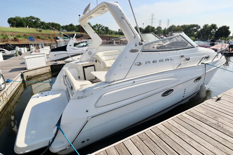 Slide: The Image of A white 2003 Regal Commodore 2860 docked at a wooden pier in a marina. - 11