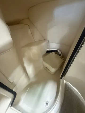 Slide: The Image of Interior view of a boat cabin with a small toilet and white walls. - 11