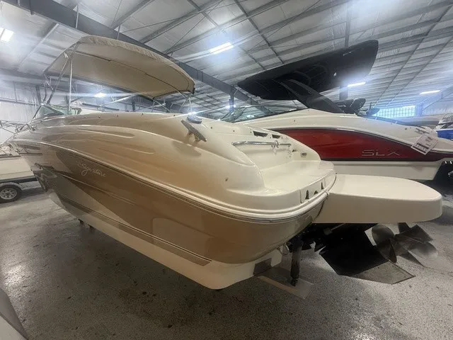 Slide: The Image of A 2001 Sea Ray 260 Signature in a storage facility. It features a beige exterior and a Bimini top. - 6