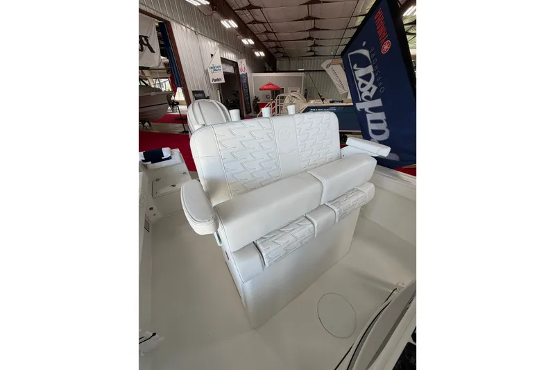 Slide: The Image of 2027 Parker 230 Coastal Elite boat interior with white cushioned seating in a showroom. - 13