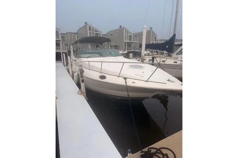 Slide: The Image of 1999 Cruisers Yachts 3075 Rogue docked at marina, surrounded by modern buildings. - 2
