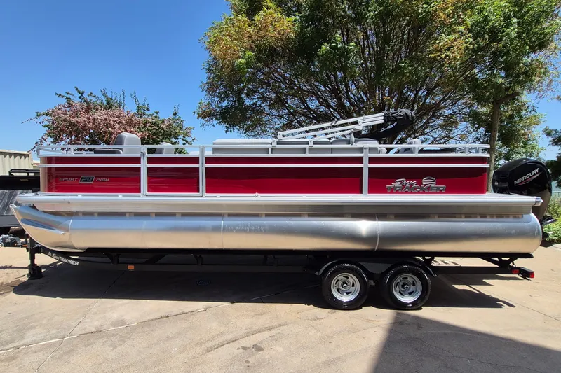 The Image of 2026 Sun Tracker Sportfish 24 XP3 pontoon boat on trailer, parked outdoors. - 0