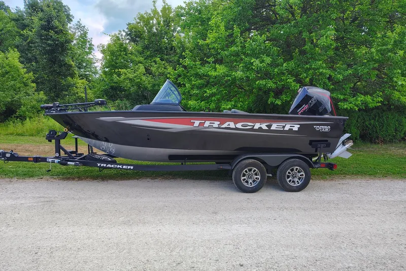 The Image of 2026 Tracker Targa V-19 WT boat on trailer, parked near lush green trees. - 0