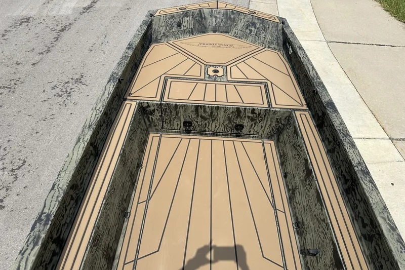 Slide: The Image of 2026 Tracker Grizzly 1650 T Prairie Wings Edition boat with camo design on pavement. - 20