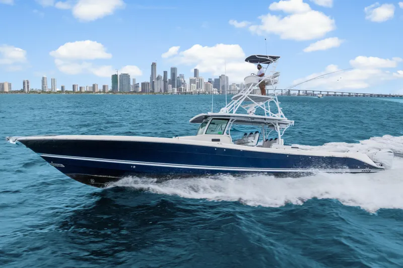 Slide: The Image of 2020 HCB 53 Suenos boat cruising on blue ocean with city skyline backdrop. - 19