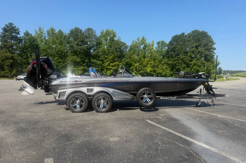 The Image of 2025 Ranger Z521R bass boat on trailer in parking lot, surrounded by trees. - 1