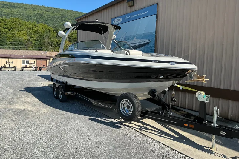 Slide: The Image of 2022 Crownline 290 SS boat on trailer, parked outside a building with scenic background. - 8