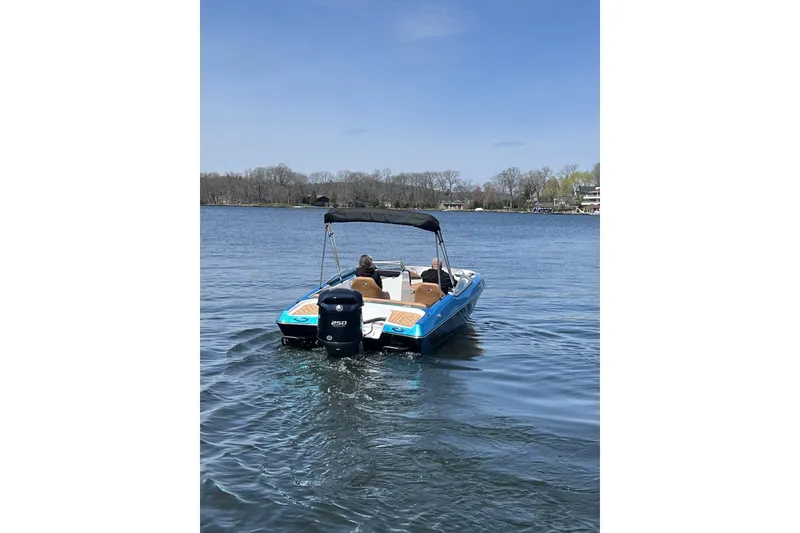 Slide: The Image of 2021 Checkmate Pulsare 2400 BRX boat cruising on a calm lake under a clear sky. - 1