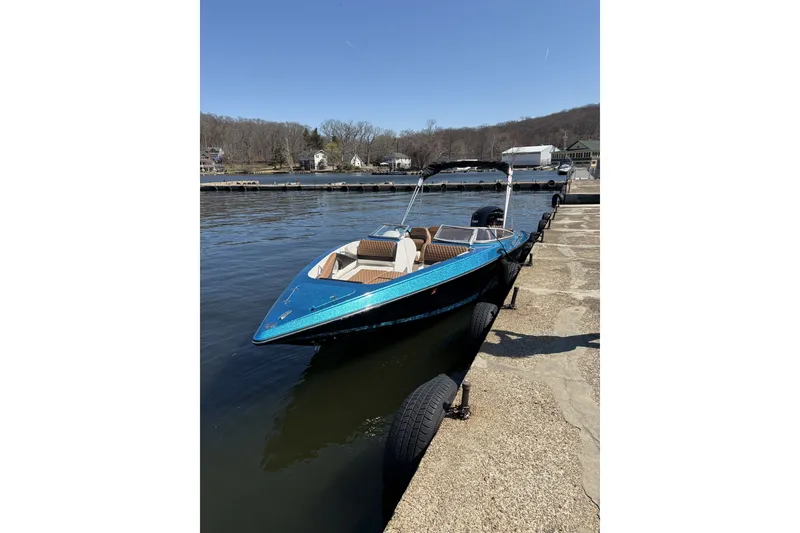 The Image of 2021 Checkmate Pulsare 2400 BRX boat docked by a serene lakeside. - 2