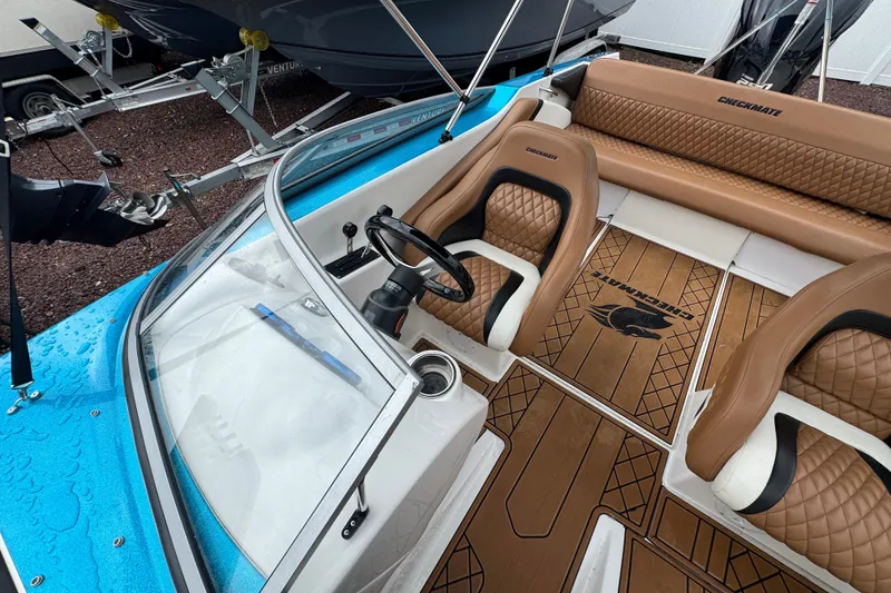 Slide: The Image of 2021 Checkmate Pulsare 2400 BRX boat interior with tan seats and wood-patterned flooring. - 29