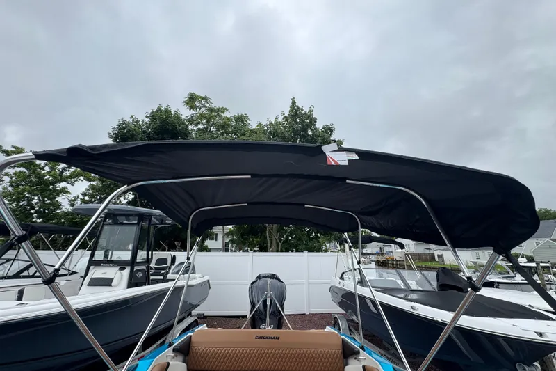 Slide: The Image of 2021 Checkmate Pulsare 2400 BRX boat with black canopy, parked outdoors. - 27