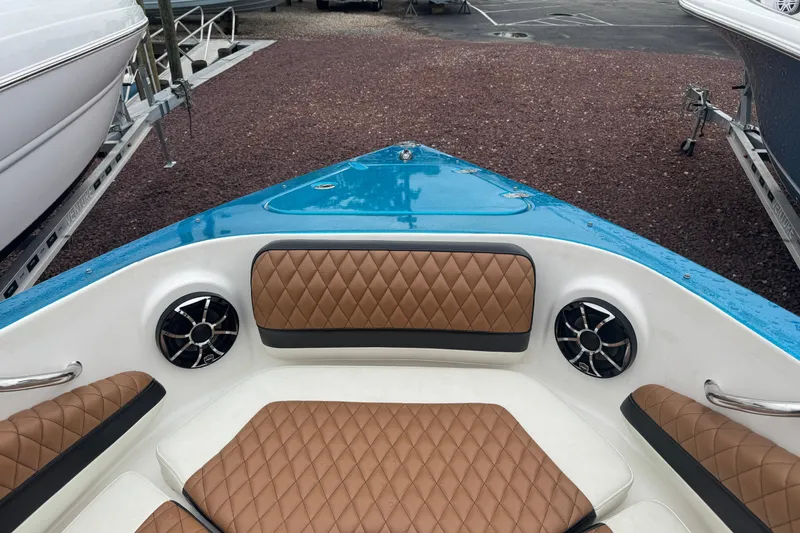 Slide: The Image of 2021 Checkmate Pulsare 2400 BRX boat interior with brown diamond-stitched seating and speakers. - 26