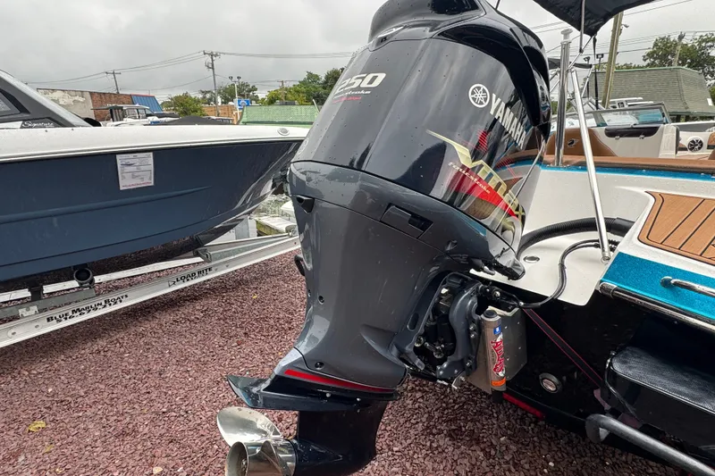 Slide: The Image of Yamaha outboard motor on 2021 Checkmate Pulsare 2400 BRX boat, parked on gravel. - 7