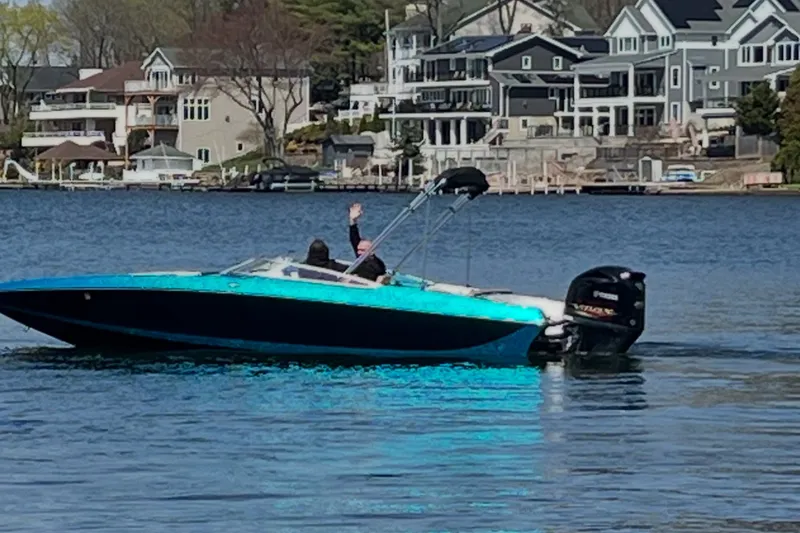 Slide: The Image of 2021 Checkmate Pulsare 2400 BRX boat cruising on a lake near waterfront homes. - 0