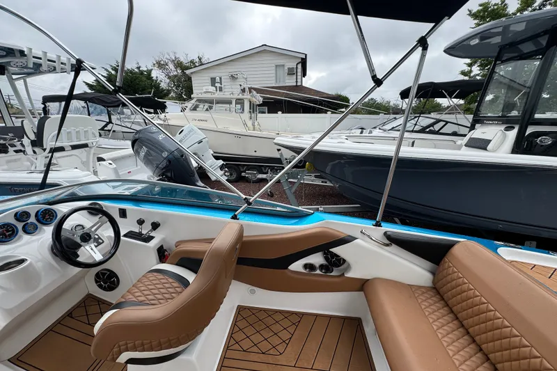 Slide: The Image of 2021 Checkmate Pulsare 2400 BRX boat interior with tan seating and modern dashboard. - 11