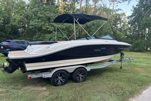 Slide: The Image of 2023 Sea Ray SPX 210 boat on trailer, parked on grass with trees in background. - 4