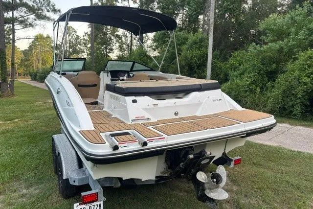 Slide: The Image of 2023 Sea Ray SPX 210 boat on trailer, parked on grass, with lush greenery background. - 2