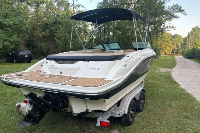 Slide: The Image of 2023 Sea Ray SPX 210 boat on trailer, parked on grass near trees. - 3