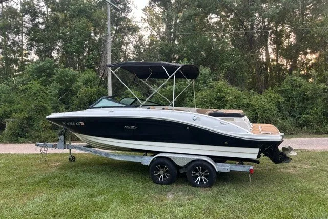 Slide: The Image of 2023 Sea Ray SPX 210 boat on trailer, parked on grass with forest background. - 1