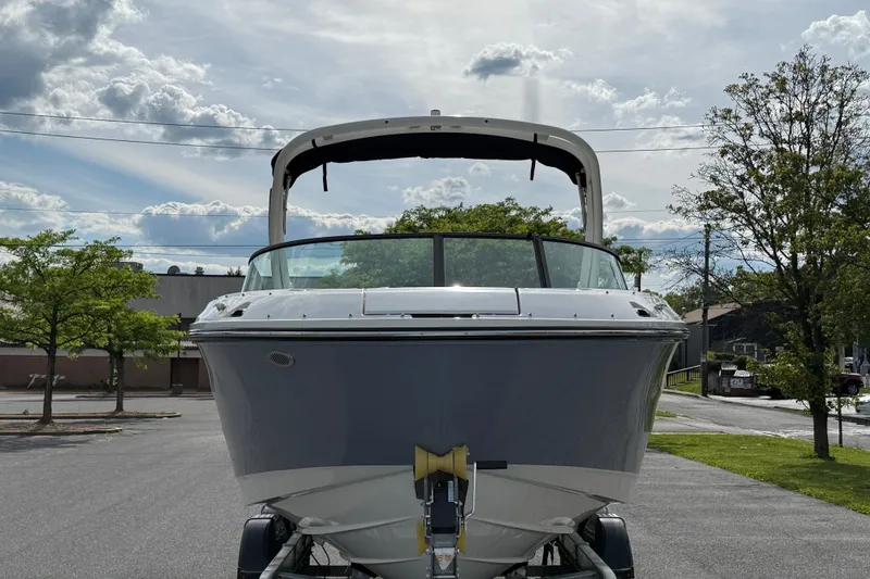 Slide: The Image of 2026 Sea Ray SDX 230 boat on trailer, parked outdoors under cloudy sky. - 2
