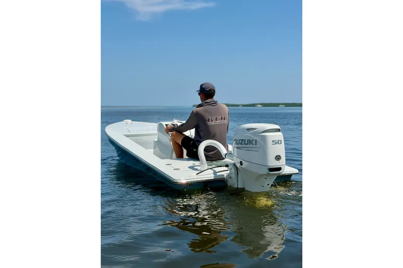 Slide: The Image of Man steering a 2024 Homeade 15 boat with Suzuki 50 engine on calm water. - 2