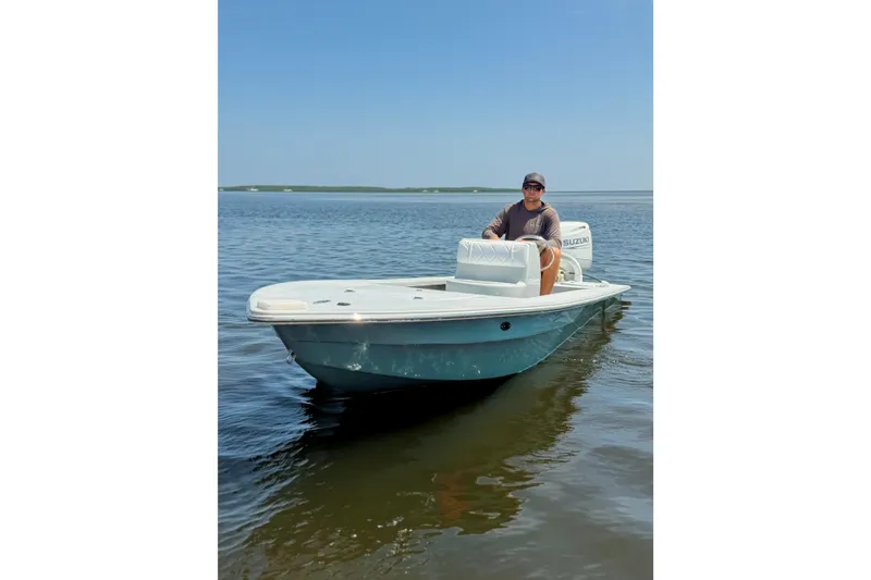 Slide: The Image of Man steering a 2024 Homeade 15 boat on calm water under clear blue sky. - 3