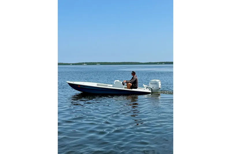Slide: The Image of Man operating a 2024 Homeade 15 boat on calm water under clear blue sky. - 5