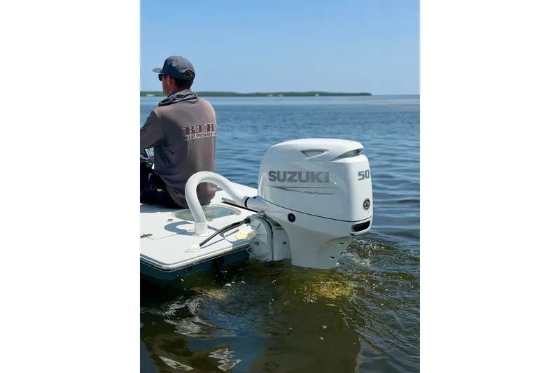Slide: The Image of Man on boat with Suzuki outboard motor, calm water, clear sky. - 14
