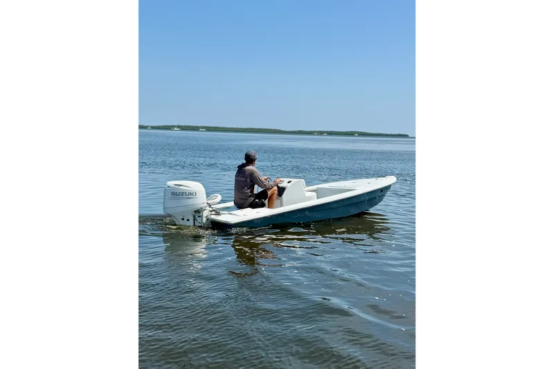 Slide: The Image of A person navigates a 2024 Homeade 15 boat with Suzuki outboard on calm waters. - 7