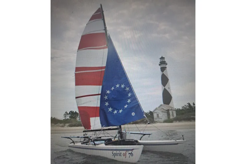 The Image of Sailboat "Spirit of 76" near lighthouse, featuring red and blue sails, Hobie Cat 21, 1989. - 1