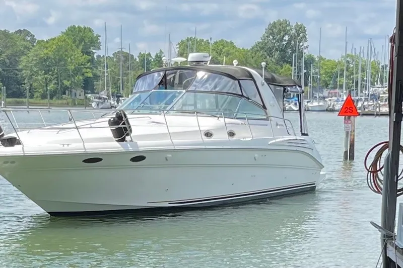 Slide: The Image of 1999 Sea Ray Sundancer 400 yacht docked in a marina with lush greenery. - 1