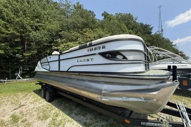 The Image of 2018 Crest Caribbean 250 SLS pontoon boat on trailer, parked outdoors. - 1