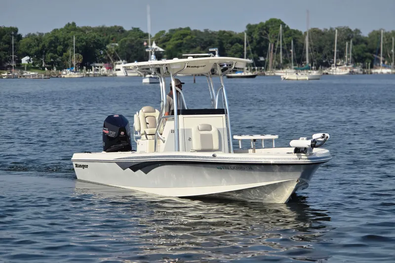 Slide: The Image of 2019 Ranger 2360 Bay Ranger boat cruising on a calm lake with trees in the background. - 2