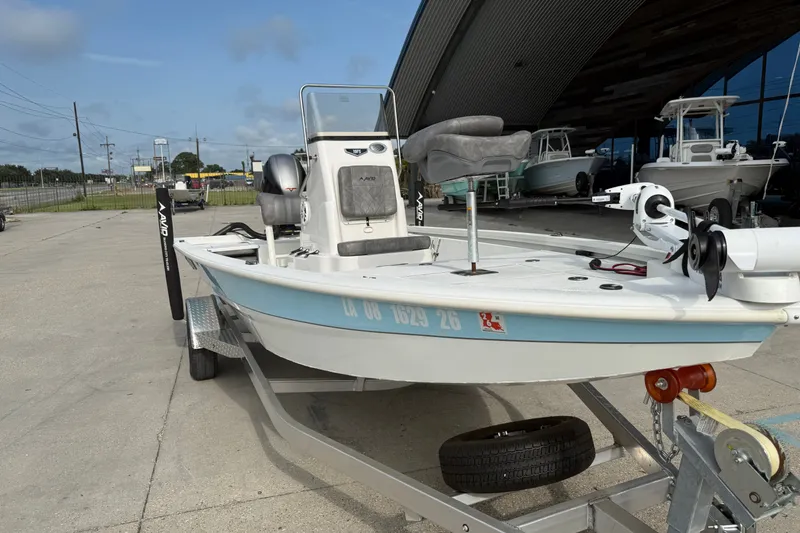 Slide: The Image of 2023 Avid 19 FS boat on trailer, parked outdoors near a showroom. - 4