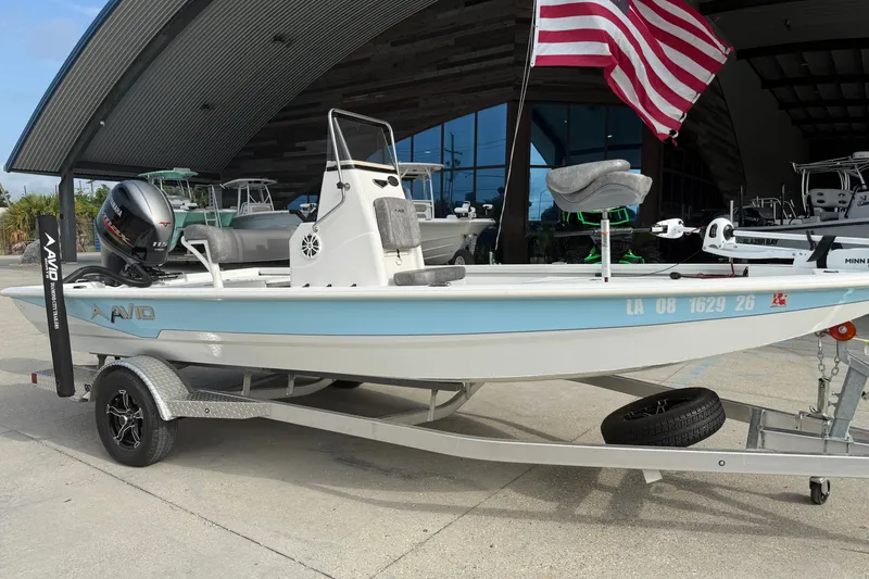 Slide: The Image of 2023 Avid 19 FS boat on trailer with American flag, displayed outdoors. - 2