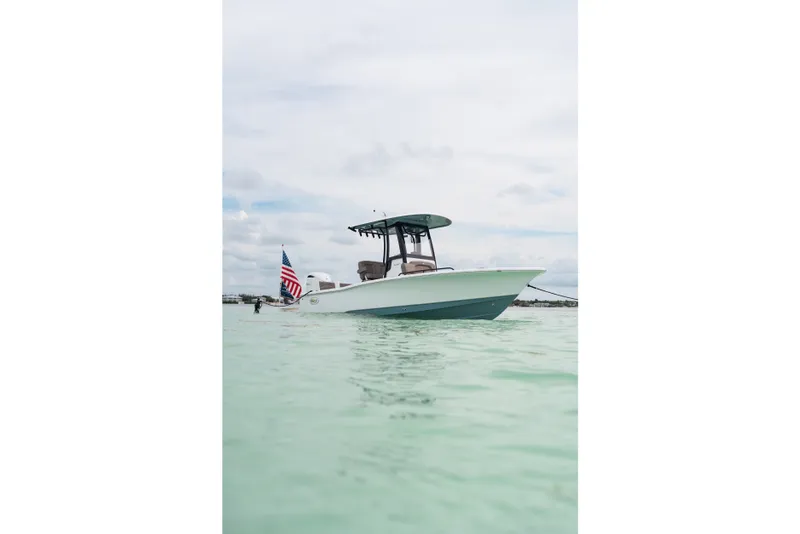 Slide: The Image of 2027 Sea Hunt BX25FS boat on calm water with American flag. - 32