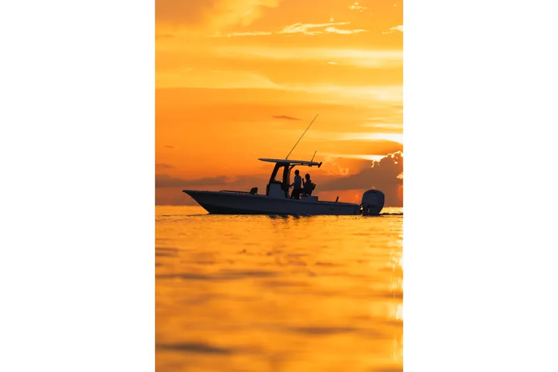 Slide: The Image of 2027 Sea Hunt BX25FS boat silhouetted against a vibrant orange sunset on the water. - 31