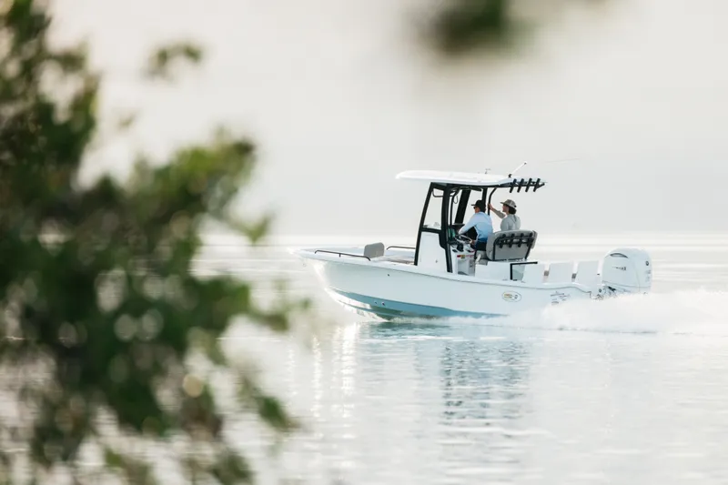 Slide: The Image of 2027 Sea Hunt BX25FS boat cruising on calm water, surrounded by blurred foliage. - 47