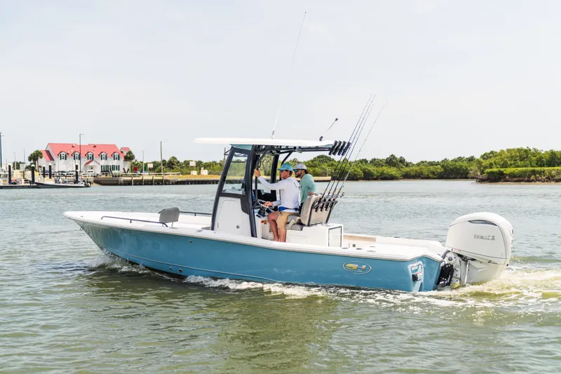 Slide: The Image of 2027 Sea Hunt BX25FS boat cruising on a calm waterway near a marina. - 26