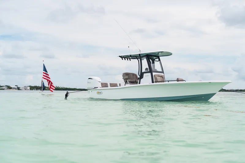 Slide: The Image of 2027 Sea Hunt BX25FS boat on calm water with American flag in background. - 33