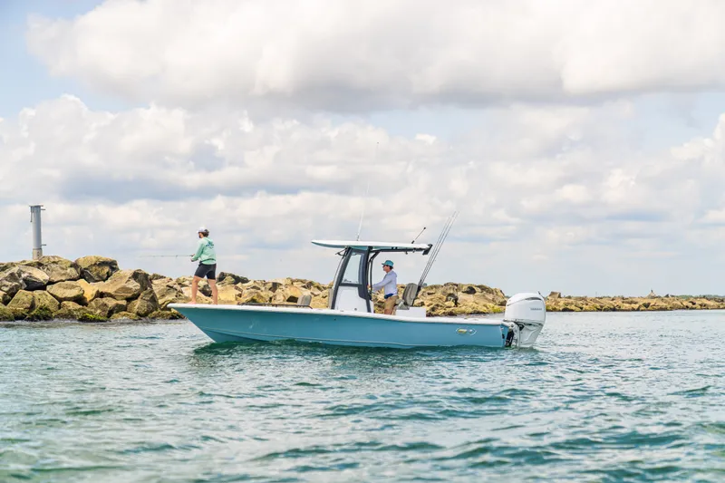 Slide: The Image of 2027 Sea Hunt BX25FS boat with anglers fishing near rocky shoreline. - 10