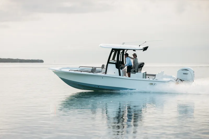 Slide: The Image of 2027 Sea Hunt BX25FS boat cruising on calm water with two passengers. - 44